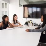 Three women sitting around a white table during a job interview